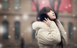 穿著冬季大衣的女子在城市中仰望飄落的雪 — 中文 壁紙