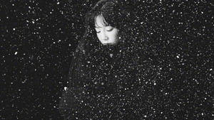 一位閉著眼睛的女子站在黑暗天空下飄落的雪中。 — 咒術迴戰 壁紙