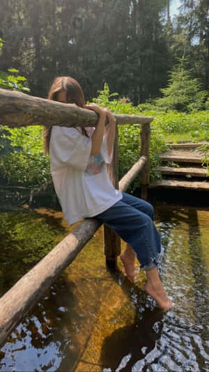 年輕女性赤腳坐在森林中小溪上的木橋欄杆上。 — 湖泊 壁紙