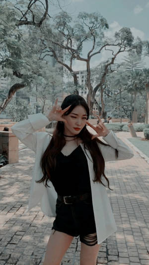 年輕女性在公園裡穿著白色西裝外套和黑色短褲，擺出手指槍的姿勢。 — 尚氣 壁紙