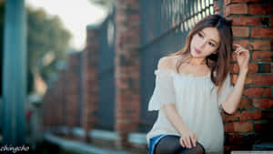 年輕女性身穿白色襯衫靠著戶外磚牆 — 可愛桌面 壁紙