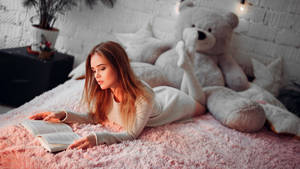 女性在臥室裡粉紅色地毯上，在大泰迪熊旁邊看書。 — 看書 GIF 壁紙