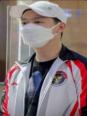 年輕印尼運動員戴口罩和隊服夾克站在屏障後 — 運動 壁紙