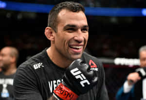 UFC拳手在八角籠中微笑，戴著手套和穿著品牌襯衫。 — 終極格鬥冠軍賽 壁紙