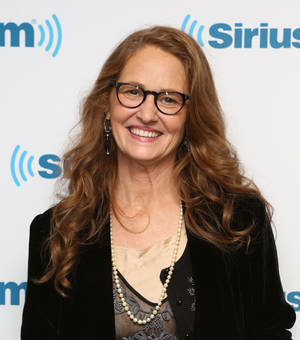 戴眼鏡和珍珠項鍊的女士在SiriusXM活動中對著鏡頭微笑。 — 女演員 壁紙