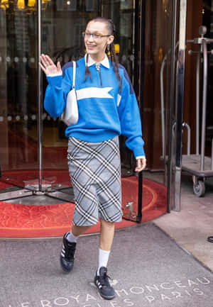 穿藍色毛衣和格子裙的女子在飯店外揮手 — 愛迪達 GIF 壁紙