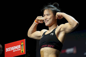 女性MMA拳手在稱重活動中穿著黑色UFC運動胸罩展示手臂。 — 運動 壁紙