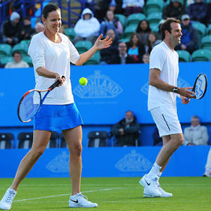 兩名網球選手微笑著在草地場上打球，背景有觀眾。 — 運動 壁紙