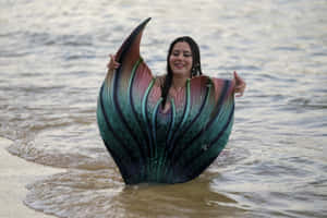 穿著彩虹美人魚尾巴的女性站在夕陽下的海中 — 美人魚 壁紙