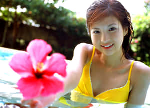 穿黃色泳衣的女性在泳池中手持粉紅色木槿花 — 模特兒 壁紙