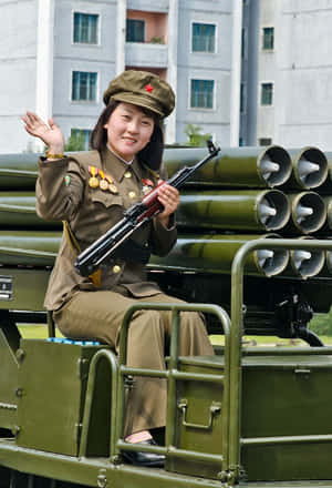 身穿軍服的年輕女子從帶有火箭發射器的軍用車輛上揮手。 — 南韓 壁紙