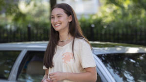 年輕女性在陽光普照的日子站在銀色車旁邊微笑。 — 酷女孩 壁紙