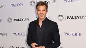 深色西裝男士在活動中微笑，身後有Yahoo和Paley Live標誌。 — 演員 壁紙