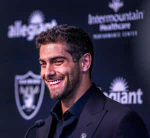 一位微笑的男士身穿西裝出席記者會，身後有團隊標誌。 — NFL 美式足球 壁紙