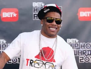男子在BET Hip Hop Awards上戴著帽子、太陽眼鏡和珍珠項鍊微笑。 — 嘻哈 壁紙
