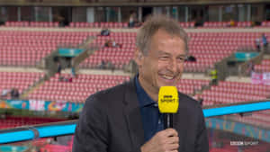 BBC Sport記者在空的體育場微笑著拿著麥克風。 — 運動 壁紙