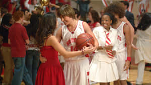 青少年籃球運動員在體育館地板上擁抱穿紅色連衣裙的女孩。 — 高中音樂劇 壁紙