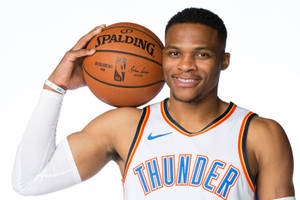 身穿雷霆隊球衣的職業籃球運動員手持 Spalding 籃球。 — 羅素·衛斯特布魯克 壁紙