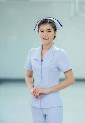 一位微笑的女護士穿著淺藍色制服和白色帽子，站在攝影棚內。 — 聽診器 壁紙