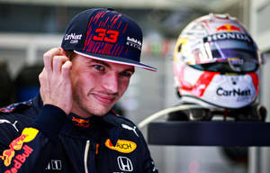 身穿 Red Bull Racing 制服的賽車手在頭盔附近調整帽子。