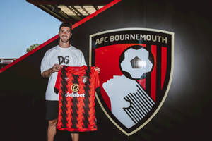 足球員在球會標誌前手持AFC Bournemouth球衣。 — 運動 壁紙
