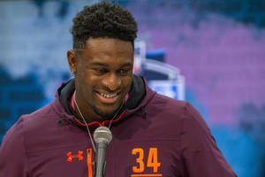 運動員穿著栗色連帽衫，號碼34，微笑著對著麥克風說話。 — Dk Metcalf 壁紙
