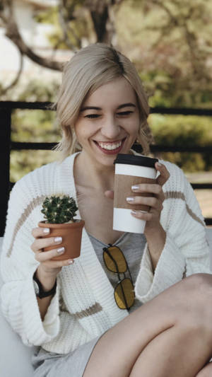 一位快樂的女性在戶外手持咖啡和仙人掌植物。 — 聖誕頌歌 壁紙