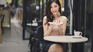女士在戶外咖啡桌旁享用甜點，配白色杯子 — 杯子蛋糕 壁紙