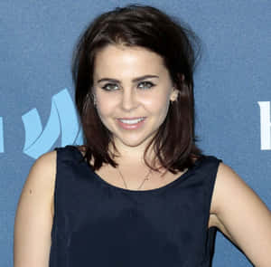 在藍色背景的活動中，穿著海軍藍連衣裙的女性對著鏡頭微笑。 — 瑪麗蓮夢露 GIF 壁紙