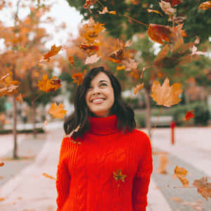穿紅色毛衣的女人笑著，落葉圍繞著她。 — 秋季 壁紙