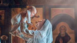 母親在教堂裡舉起嬰兒，身後有宗教圖標 — 教堂 壁紙