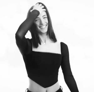 一位女性在黑白肖像中笑著，手放在頭上。 — 查莉·XCX 壁紙