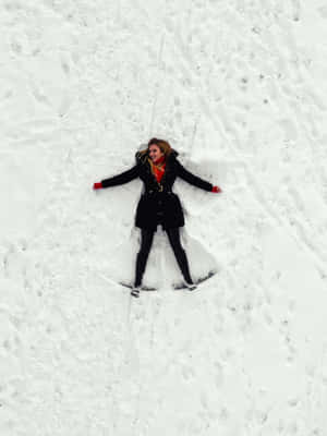 女性在雪地上穿著黑色外套和紅色手套做出雪天使。 — 可愛的雪 壁紙