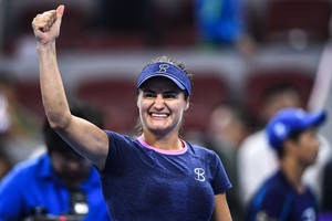 女網球運動員在燈光球場上微笑並高舉拳頭慶祝勝利。 — 運動 壁紙