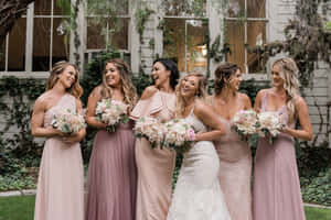 新娘和伴娘們穿著粉紅色裙子，在花園裡拿著花束大笑。 — 婚紗 壁紙