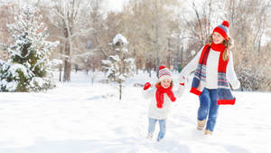 母親和女兒在陽光明媚的冬日裡在雪地公園玩耍。 — Running 壁紙