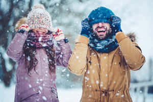 一位父親和女兒穿著厚實的冬衣，在雪中一起大笑。 — 寒冷 壁紙