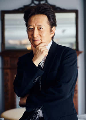 一位衣著得體的男士身穿西裝，在室內手托下巴，擺出沉思的姿勢。 — 阿基拉 壁紙