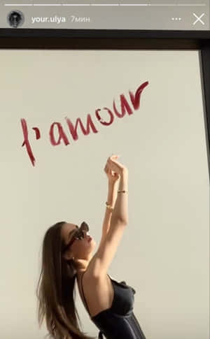 戴太陽眼鏡的女性伸手觸向白色牆上的紅色草書文字。 — Instagram限時動態 壁紙