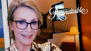 戴眼鏡的女性在溫暖照明的室內環境中微笑，有樓梯和燈。 — 女演員 壁紙