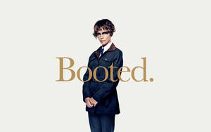 一位戴眼鏡、身穿深色外套的年輕人，以及以金色顯示的「Booted.」字樣。 — 坎迪曼 壁紙