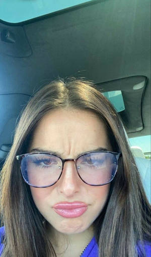 戴眼鏡的女性在車內做鬼臉。 — 艾迪生·雷 壁紙