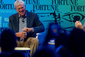 一位長者在Fortune活動中發言時微笑，前景有觀眾。 — 桌面 壁紙