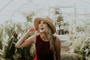 一位戴草帽的微笑女士在充滿綠色植物的溫室中。 — 美麗的公主 壁紙