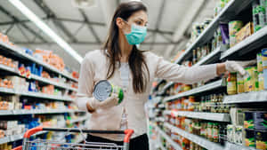 戴著口罩和手套的女性在超市通道中選購罐頭食品。 — 購物 壁紙