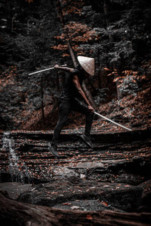 戰士在瀑布附近的秋林中持劍跳躍 — 混沌武士 壁紙