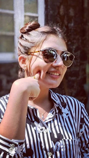戴著太陽眼鏡和條紋襯衫的女性微笑著觸摸臉頰。 — 女演員 壁紙