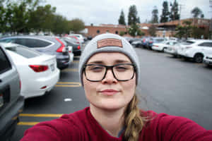 戴眼鏡和毛帽的女子在停車場自拍 — 女孩 壁紙