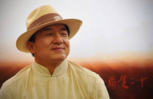 戴米色帽子和襯衫的男子在日落中微笑，背景有中文字。 — 漸層 壁紙