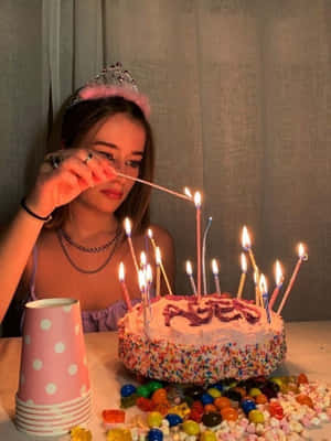 戴著頭飾的年輕女子在一個有糖果的蛋糕上吹熄生日蠟燭。 — 慶祝 壁紙